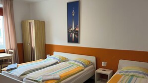 Habitación de hotel con dos camas, un escritorio, un armario y una pintura de un paisaje urbano en la pared.