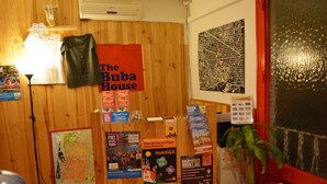 A wooden wall with a map, a red sign reading "The Buba House", and various travel posters. - The Buba House - Hostel (Barcelona)