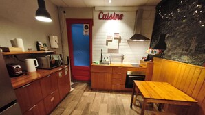 A compact kitchen with wooden cabinets, a microwave, a coffee maker, and a sink. - The Buba House - Hostel (Barcelona)