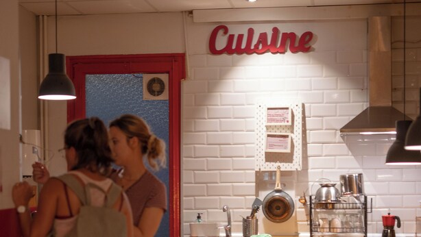 A kitchen area with a 'Cuisine' sign, wooden cabinets, a sink, and a stove. - The Buba House - Hostel (Barcelona)