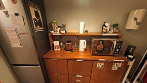 A compact kitchen with a refrigerator, microwave, and a coffee maker. - The Buba House - Hostel (Barcelona)