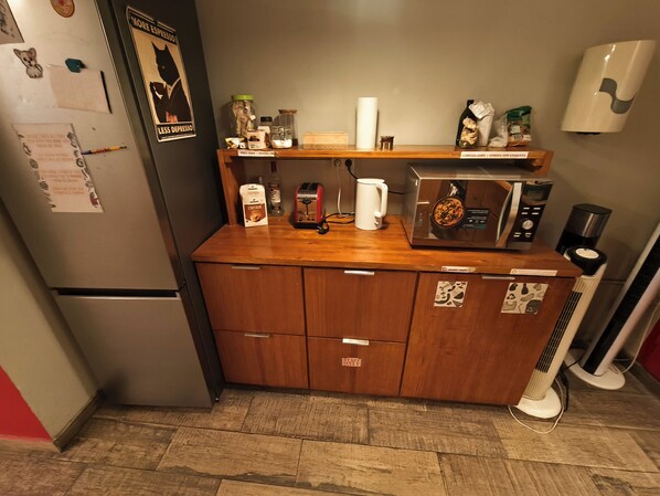 A compact kitchen with a refrigerator, microwave, and a coffee maker. - The Buba House - Hostel (Barcelona)