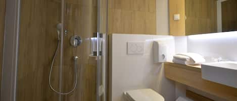 A modern bathroom with a glass-enclosed shower, a white toilet, and a wooden vanity with a sink.