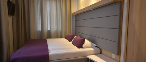 Una habitación de hotel moderna con cama, mesita de noche y cabecera.
