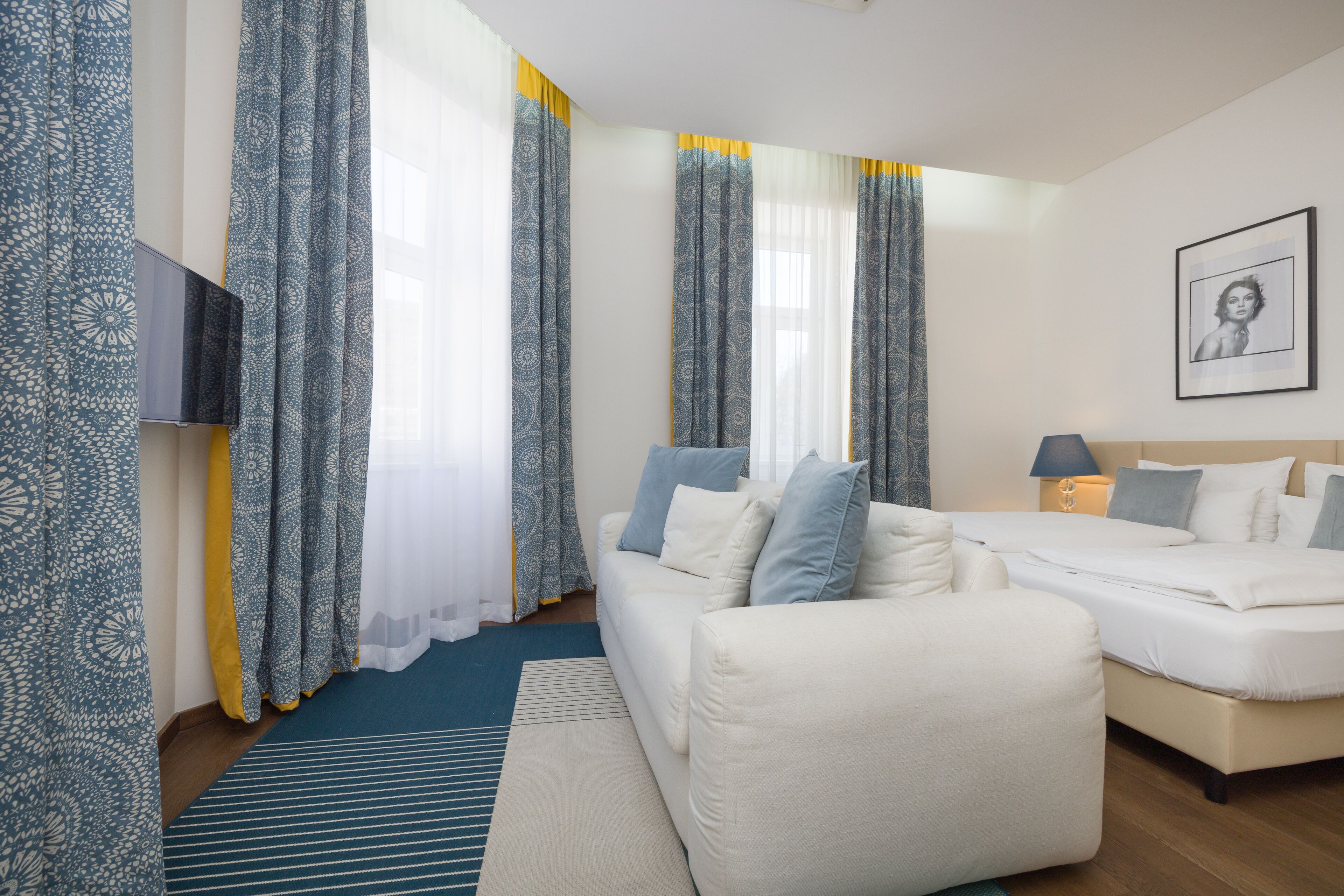 A modern hotel room with a sofa, a bed, and a TV.