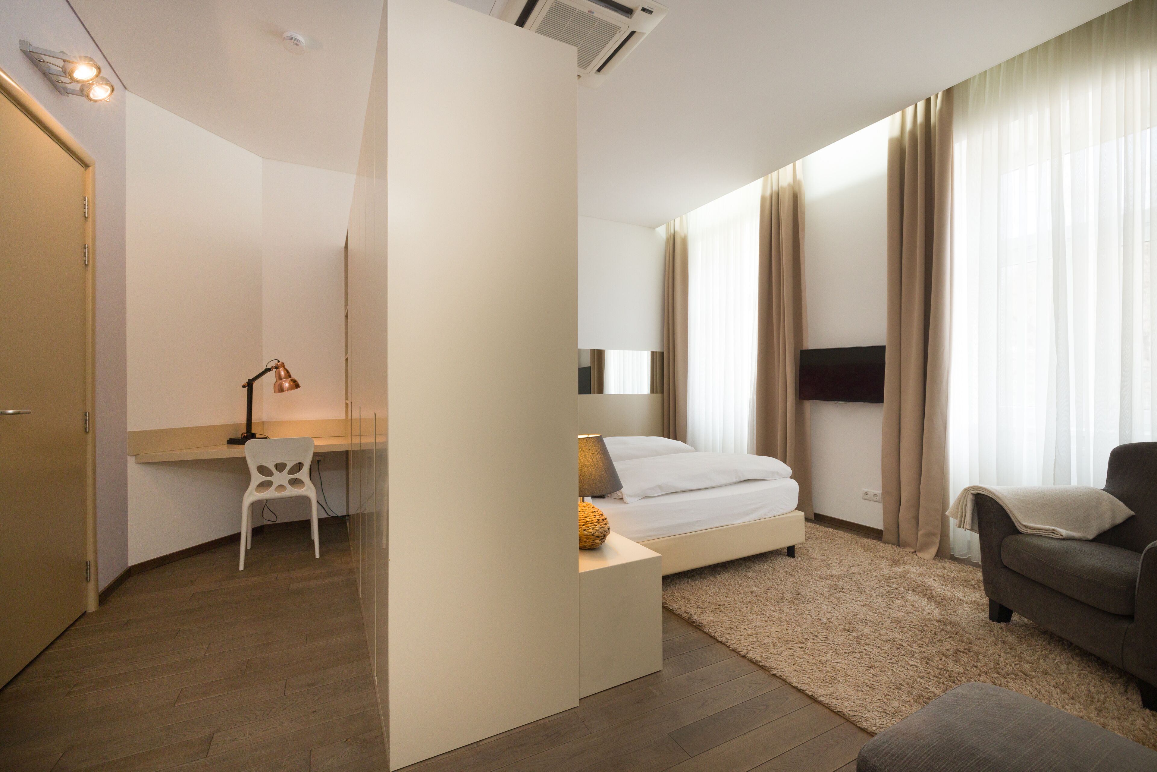 Una habitación de hotel moderna con cama, escritorio, silla y sofá.
