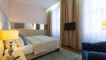 Habitación de hotel con cama, televisor, lámpara, control remoto y un sillón azul.