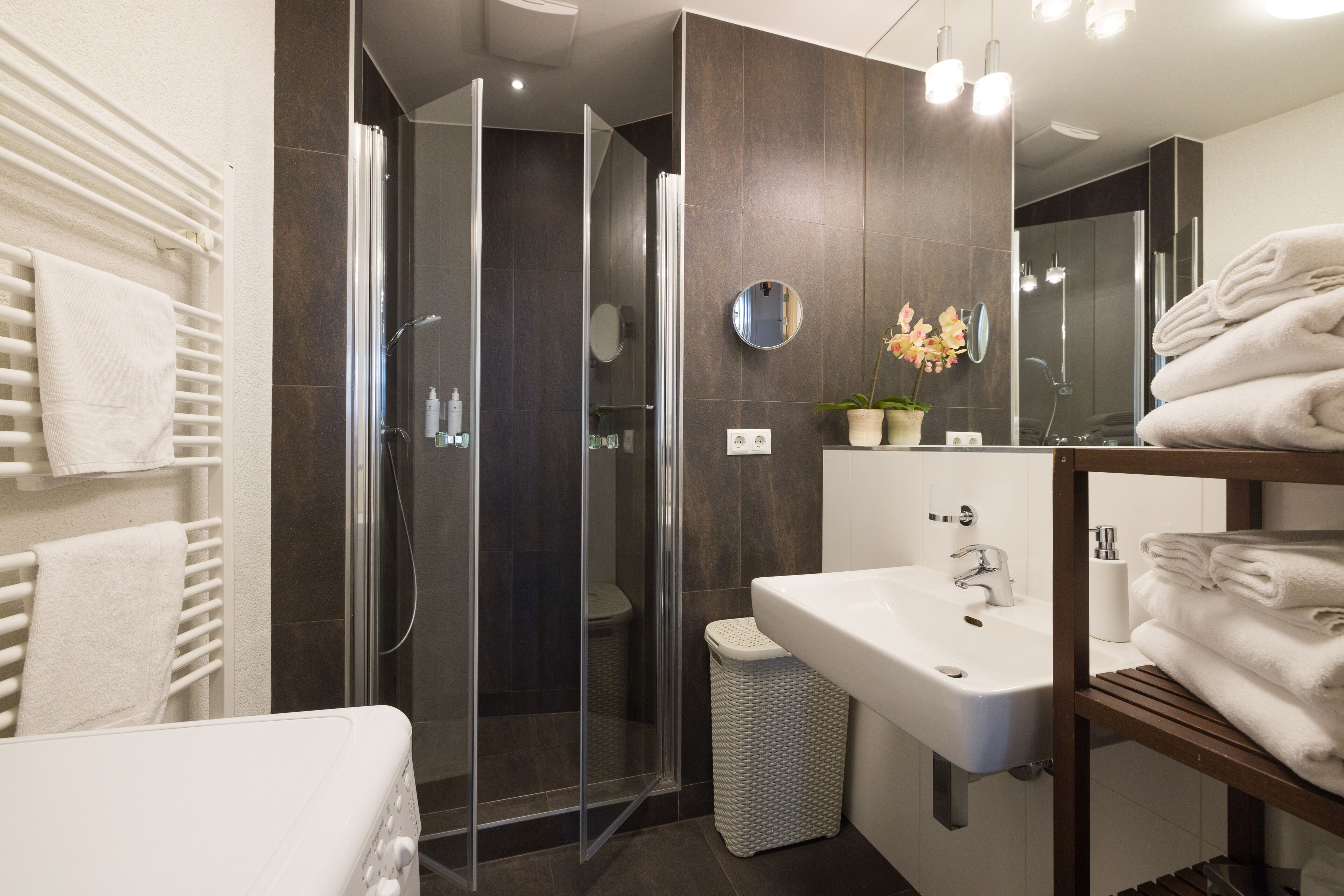 Une salle de bain moderne avec une douche à parois de verre, un lavabo et un miroir.