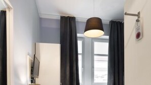 Habitación de hotel con un ventanal grande, una lámpara de techo y una puerta con picaporte.