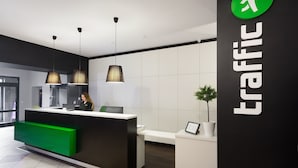 Una moderna zona de recepción con una paleta de colores blanco y negro, un mostrador verde e iluminación colgante.