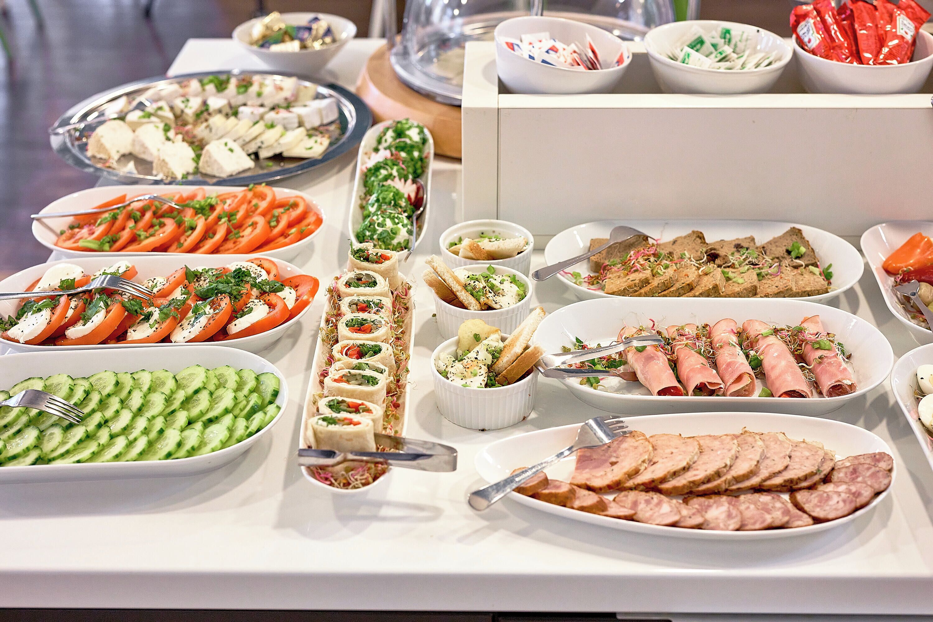Een buffet met diverse gerechten, waaronder vleesschotels, groenten en salades.
