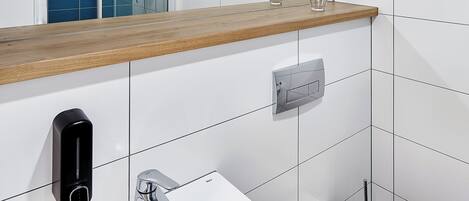 A modern bathroom with a white sink, mirror, and wooden countertop.