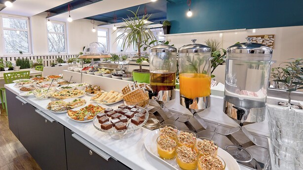 Un bufé con distintos alimentos y bebidas, incluyendo gofres, postres y una estación de café.