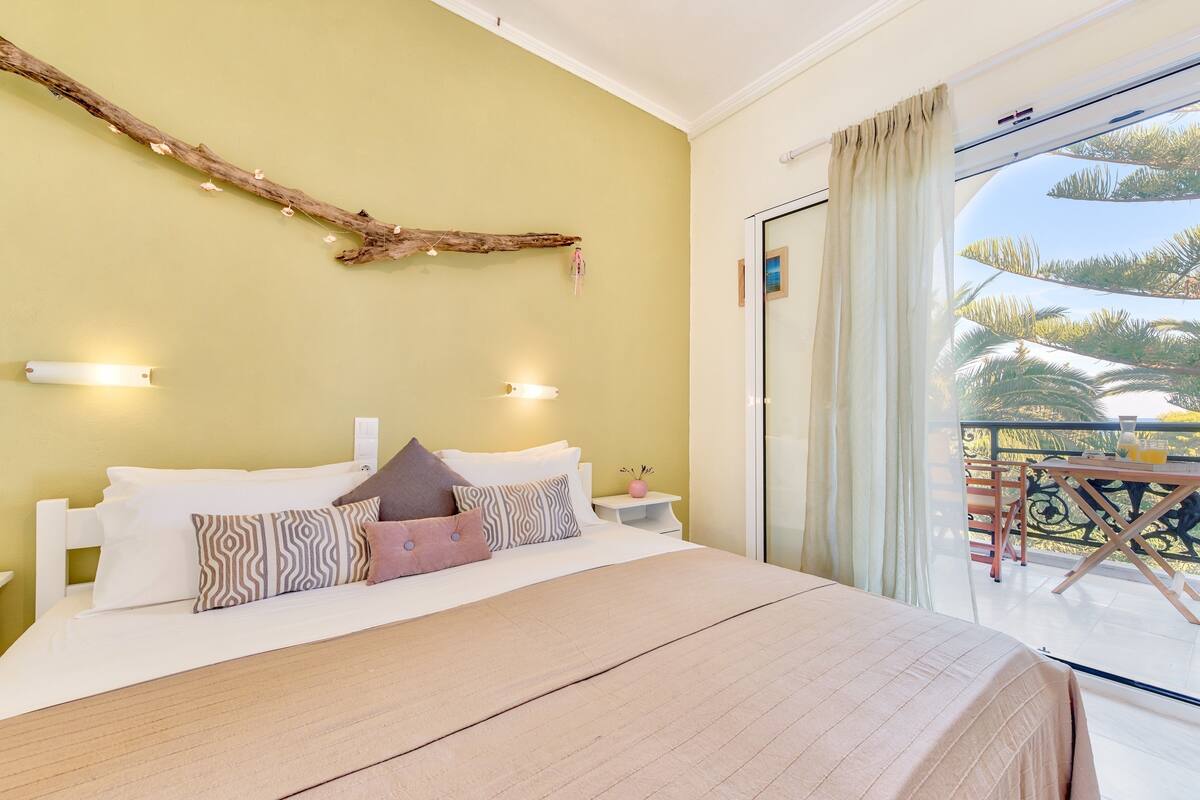 A bedroom with a bed, bedside tables, and a balcony with a railing.