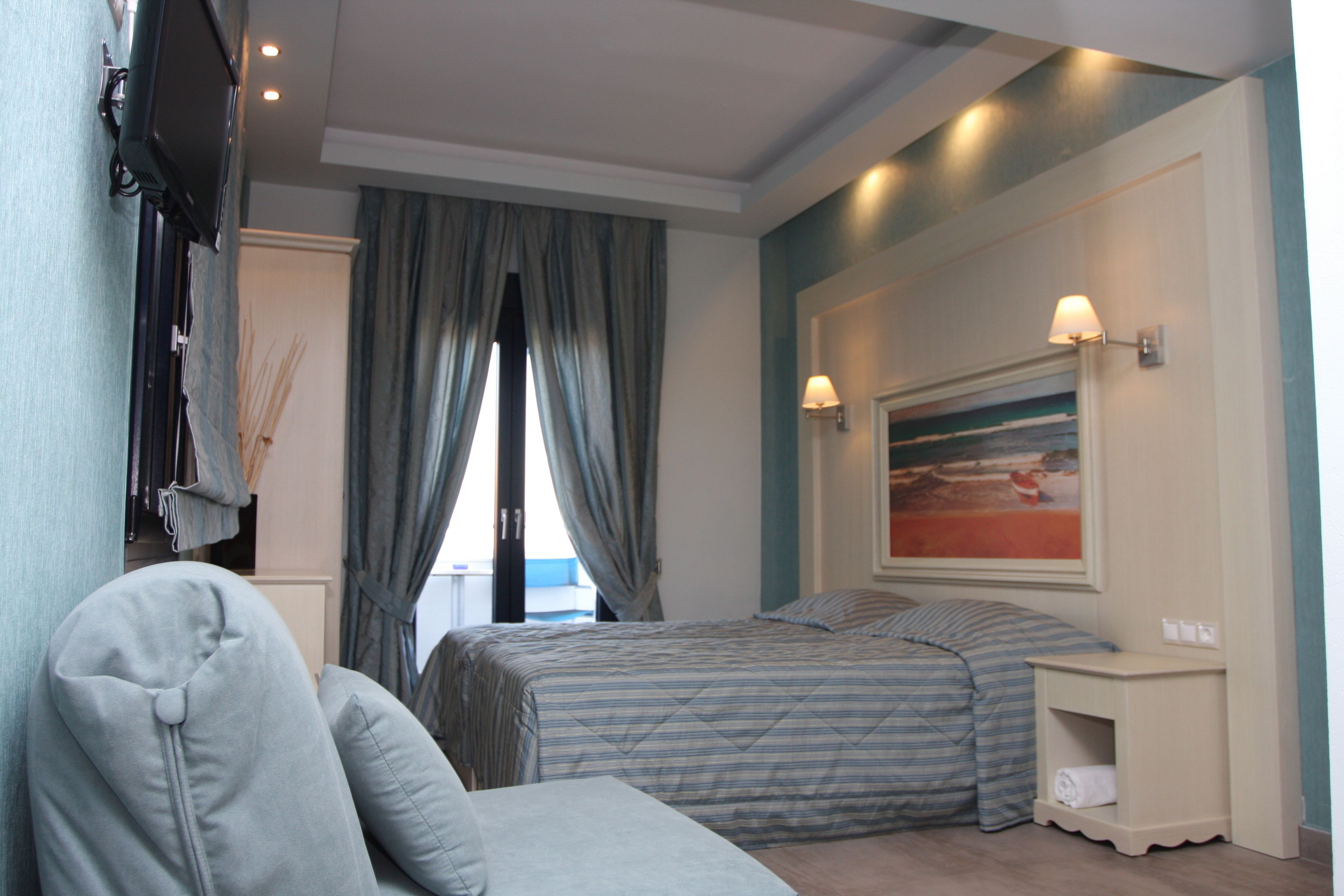Habitación de hotel con cama, mesita de noche, lámpara y un cuadro en la pared.