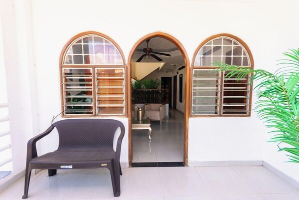 A room with a bench, a ceiling fan, and a view into another room through an arched doorway.