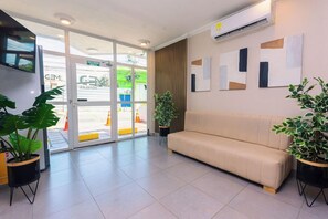 A hotel lobby with a beige sofa, potted plants, and abstract wall art.