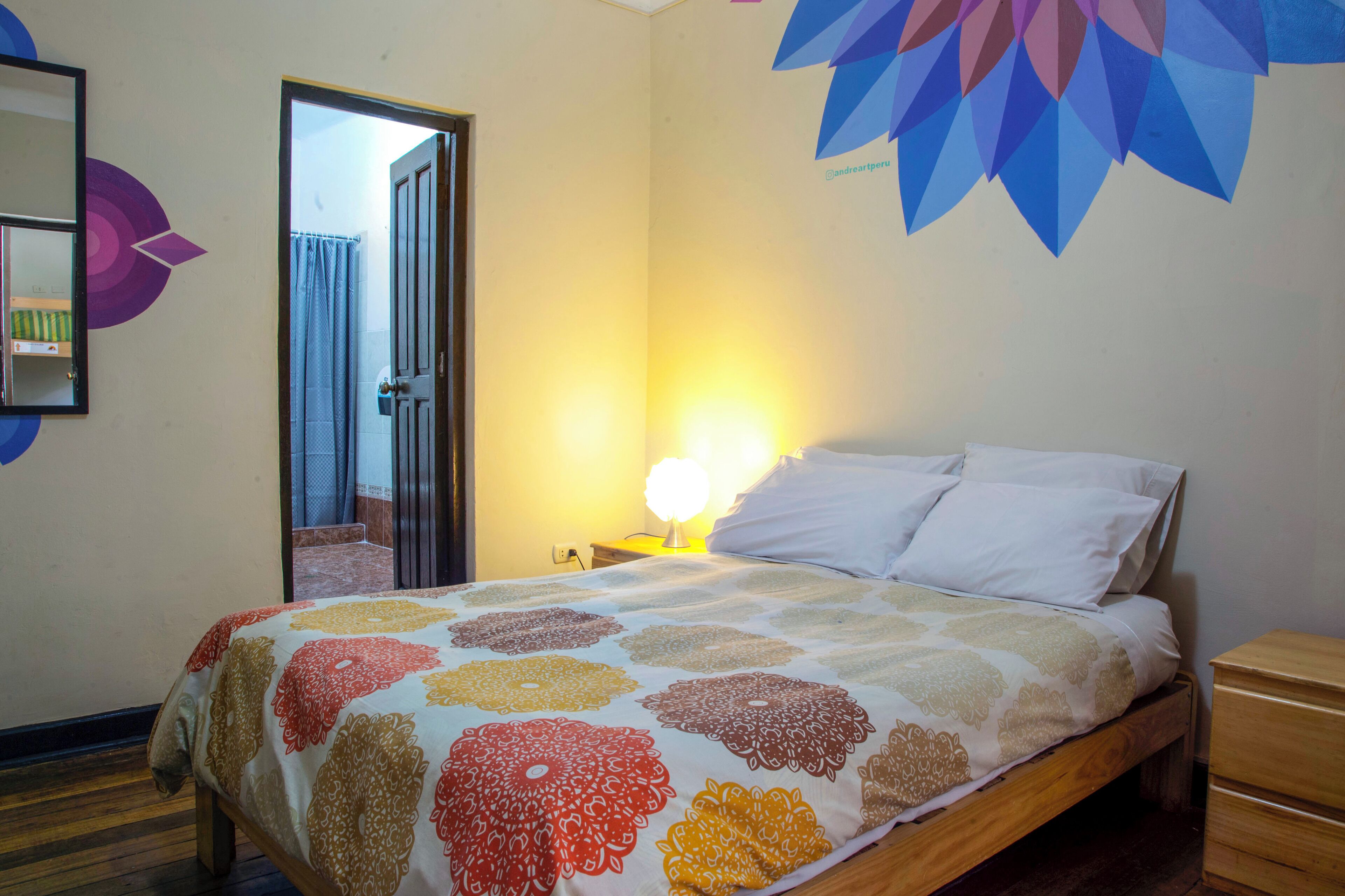 Un dormitorio con cama, mesita de noche, cómoda de madera y puerta que da a otra habitación.