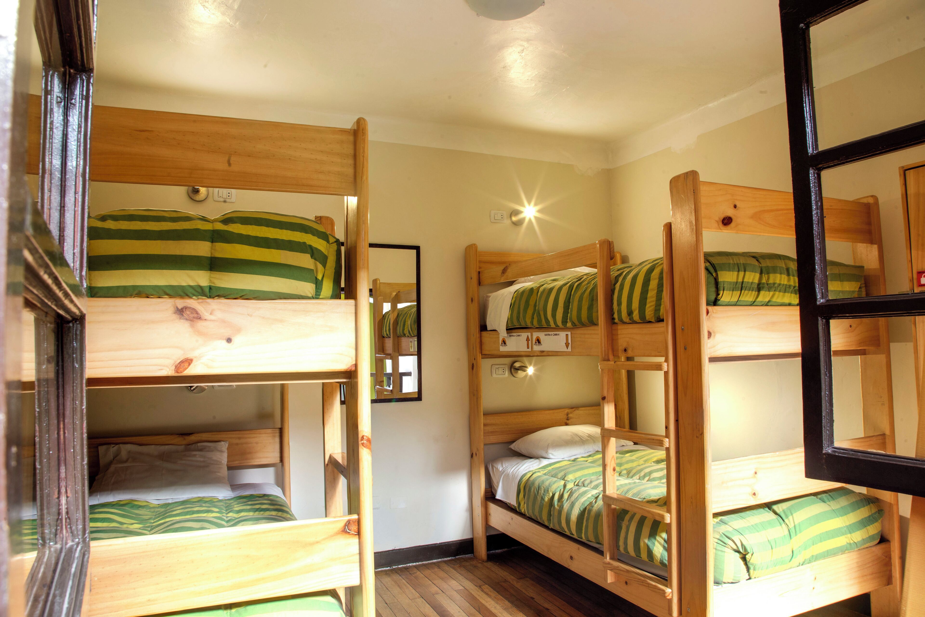 Une chambre avec des lits superposés, des têtes de lit en bois et un miroir.