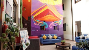 Un vestíbulo vibrante con un mural colorido, sofás azules y una pequeña mesa de centro.