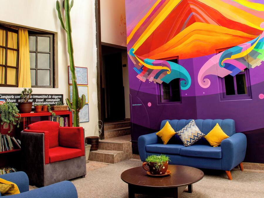 Un salón vibrante con un mural colorido, un cactus y un sofá azul con cojines amarillos.