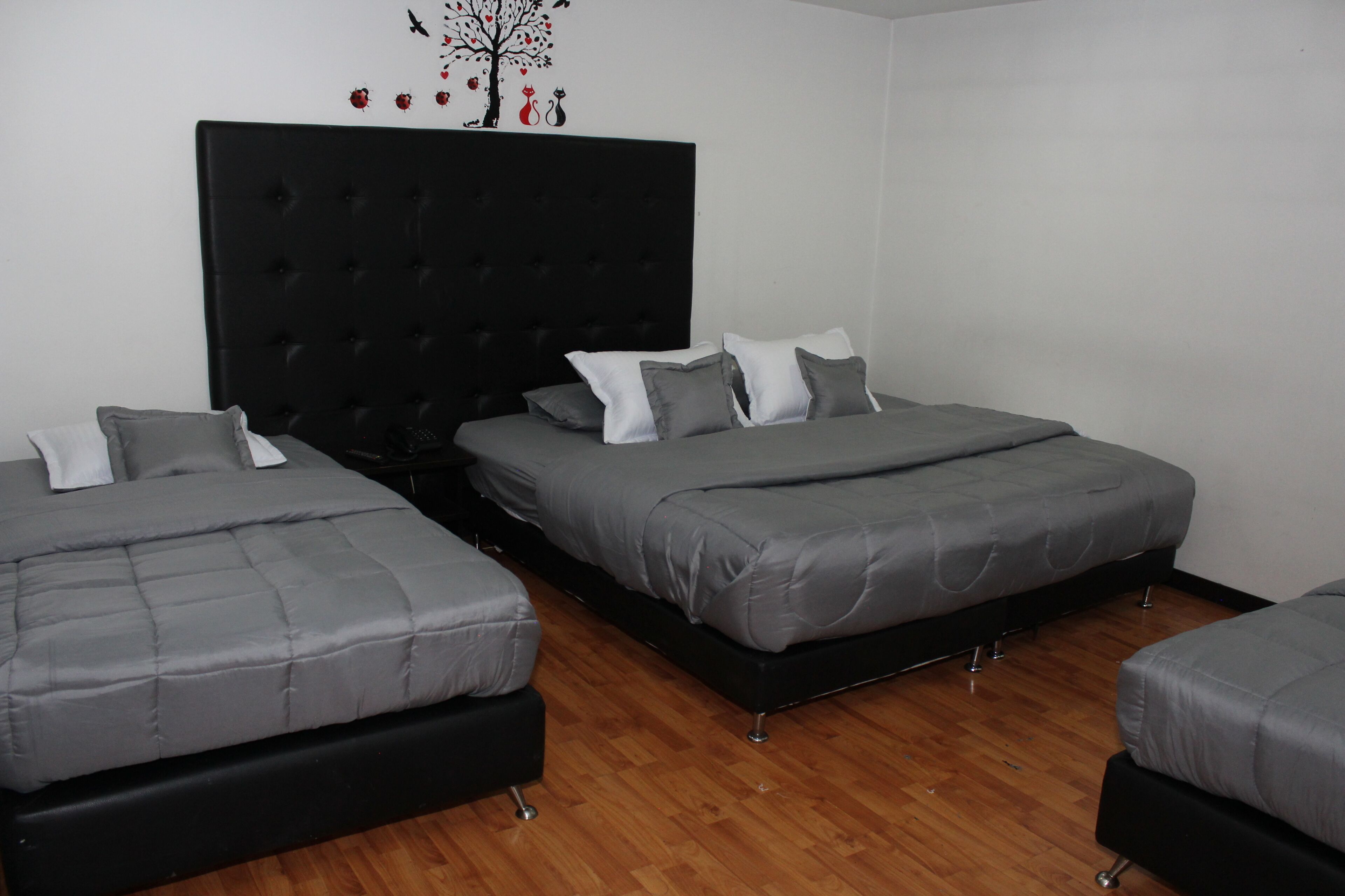 A room with two beds, a black headboard, and a wooden floor.