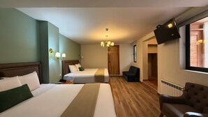A hotel room with two beds, a chair, a TV, and a wooden floor. - Hotel Monasterio San Pedro (Cusco)