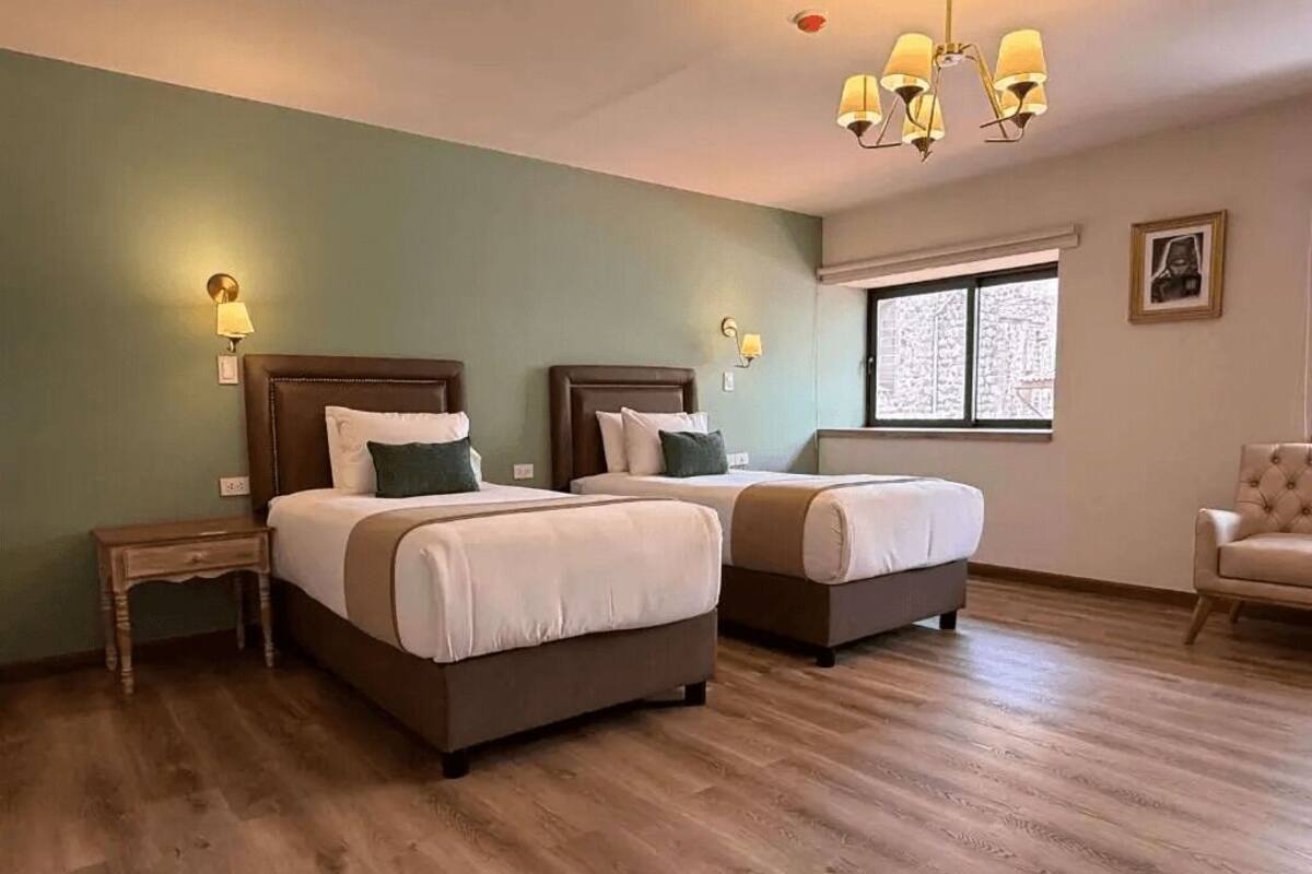 Ein Hotelzimmer mit zwei Betten, Holzboden, einem Fenster mit Blick und einem Kronleuchter.