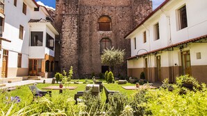 A courtyard with stone buildings, a central tower, and outdoor seating areas. - Hotel Monasterio San Pedro (Cusco)