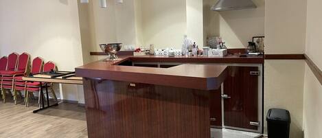 Una cocina moderna con encimera de madera, un fregadero y una estufa. Se ven sillas rojas y una mesa al fondo.