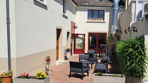 A courtyard with outdoor seating, a red door, and potted plants. - Au Relais Nivernais (Nevers)
