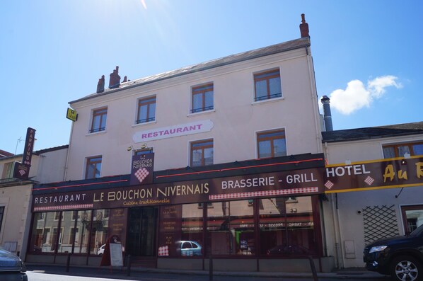 Un edificio con restaurante y parrilla en la planta baja y un hotel en los pisos superiores.