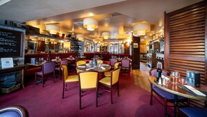 A restaurant with multiple dining tables and chairs, a bar area, and a kitchen visible in the background. - Au Relais Nivernais (Nevers)