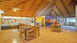 A spacious indoor area with high ceilings and wooden tables and chairs. - Fort Manor (Kochi)