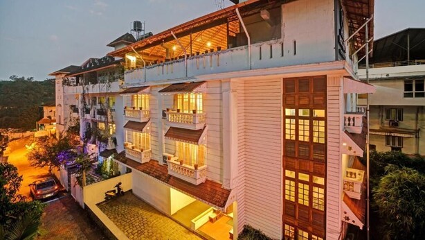A multi-story hotel with balconies, a covered outdoor area, and a paved driveway. - Fort Manor (Kochi)