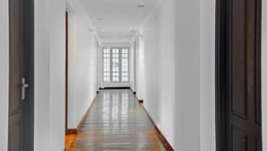 A long, narrow hallway with white walls and a wooden floor. - Fort Manor (Kochi)