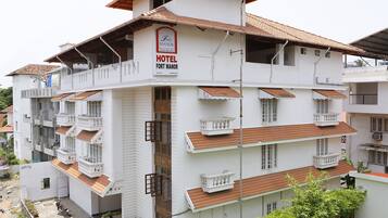 Un hotel de varios pisos con balcones, un cartel que dice "Fort Manor Hotel" y un techo de tejas.