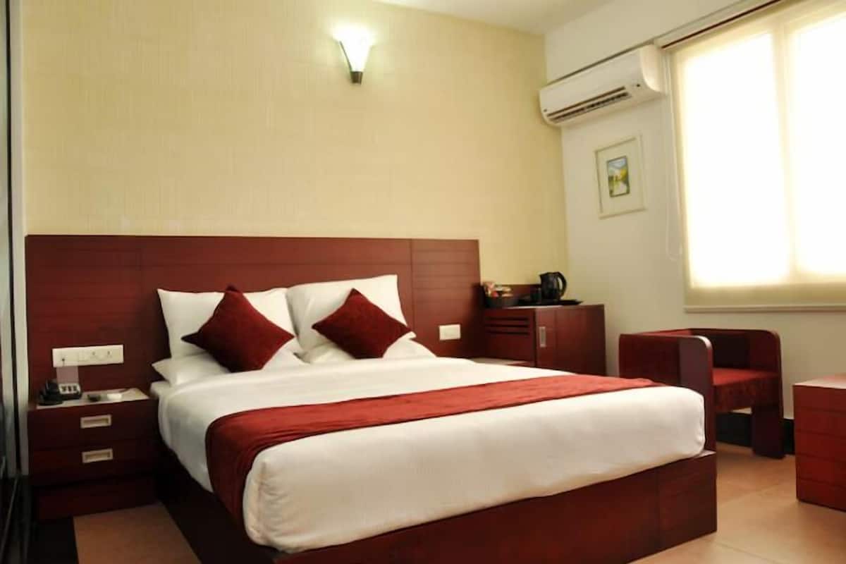 A hotel room with a large bed, a nightstand, a desk, and a chair.