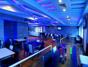 Un restaurante moderno con iluminación azul, pisos de madera y una zona de bar.