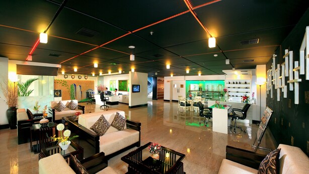 A spacious lobby with a reception desk, seating area, and a shoe display. - Olive Eva (Kanayannur)