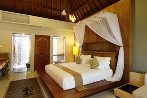 A spacious bedroom with a large bed, wooden headboard, and a canopy. - Swarapadi Villa (Ubud)