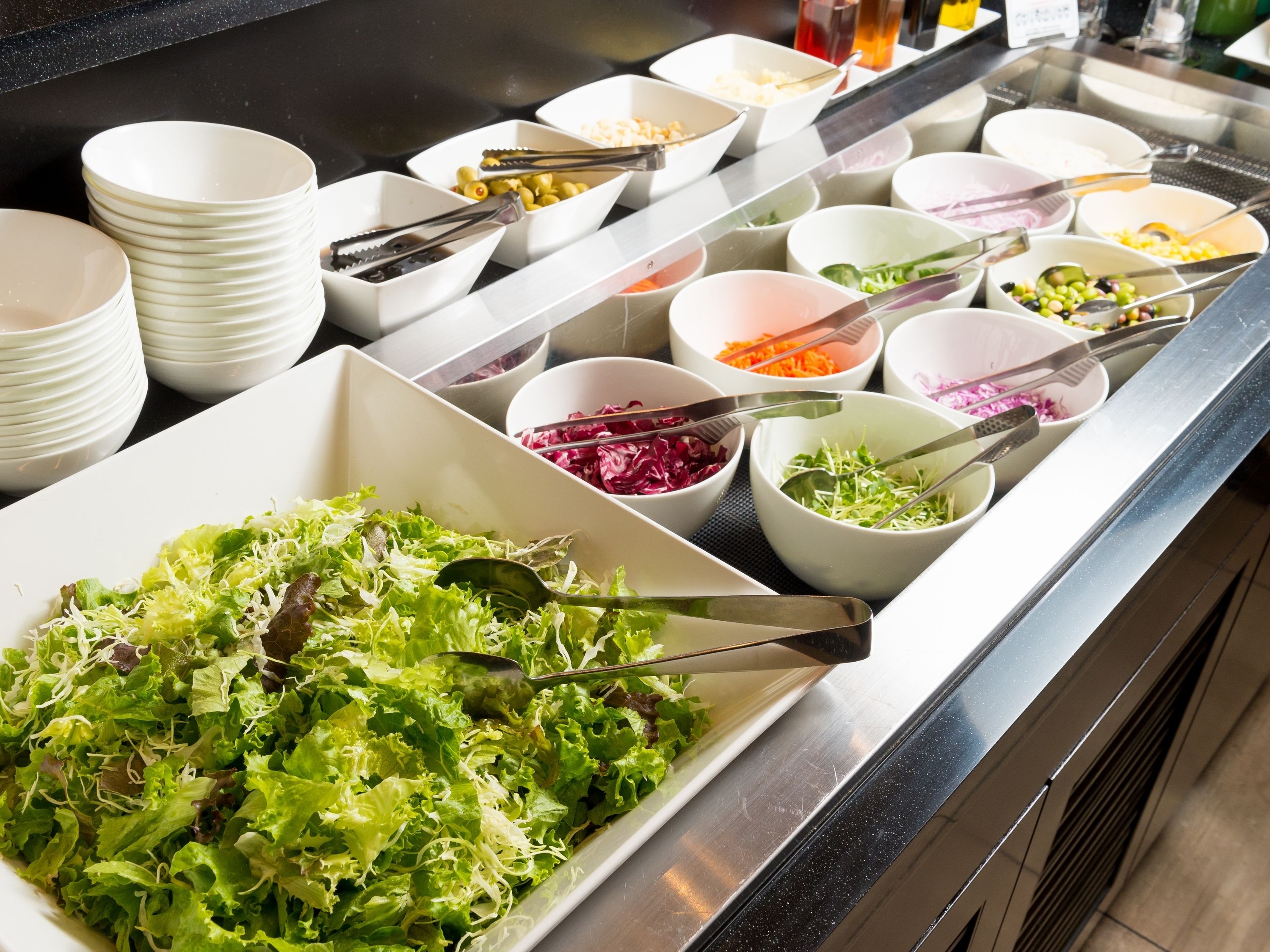 A buffet with various dishes including salads, vegetables, and grains.