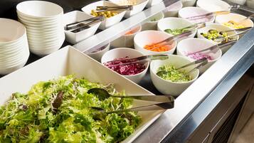 A buffet with various dishes including salads, vegetables, and grains.