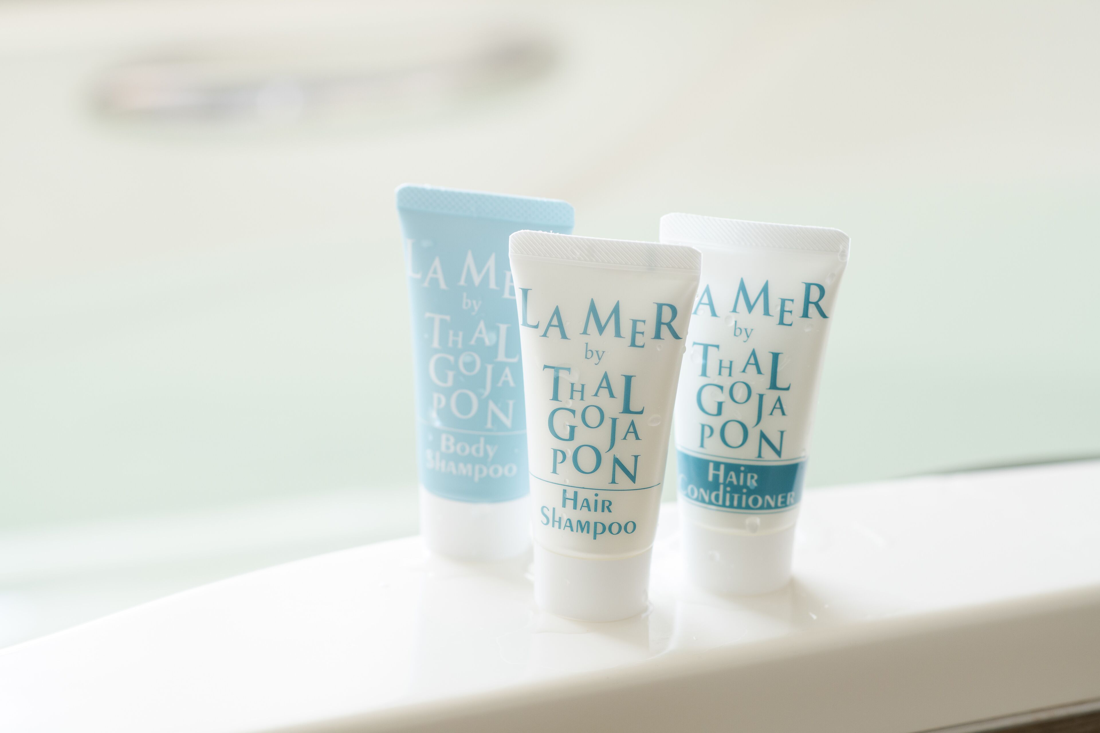 Three toiletry bottles labeled 'Lamer by Thai Goja' on a white surface.