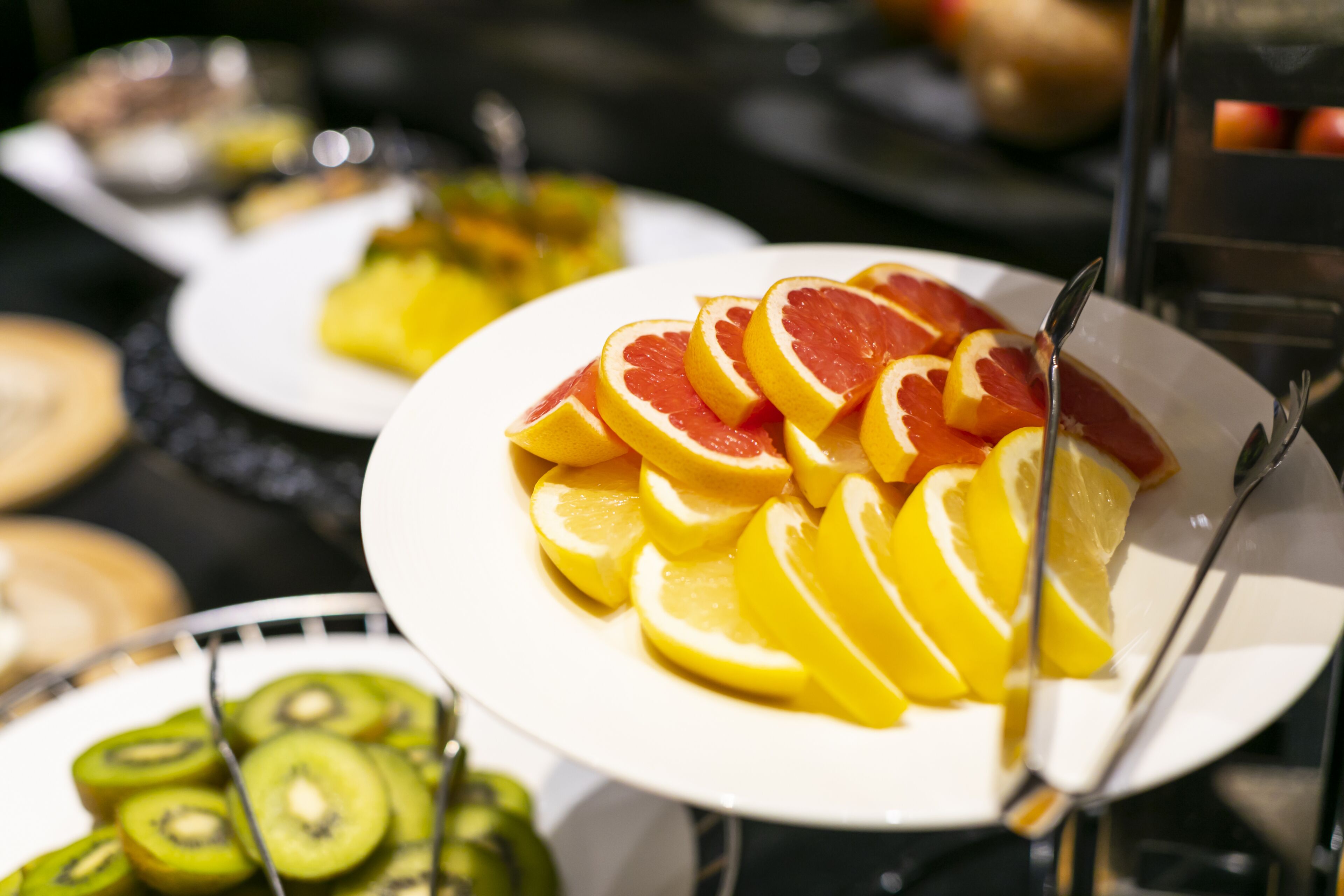 A buffet with various fruits including oranges and kiwi slices.