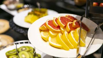 A buffet with various fruits including oranges and kiwi slices.