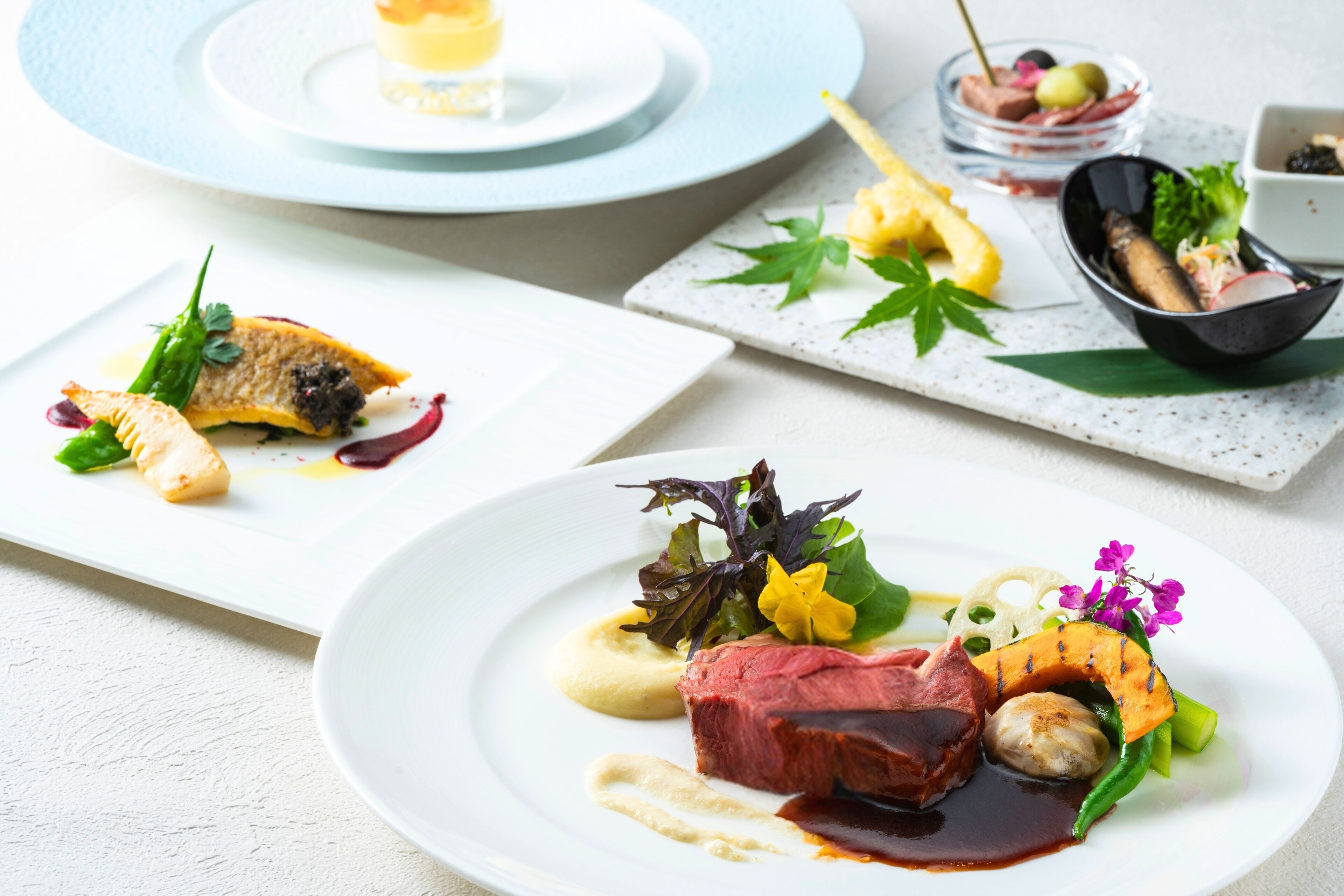A table set with various dishes, including a steak and vegetables, and a bowl of olives.
