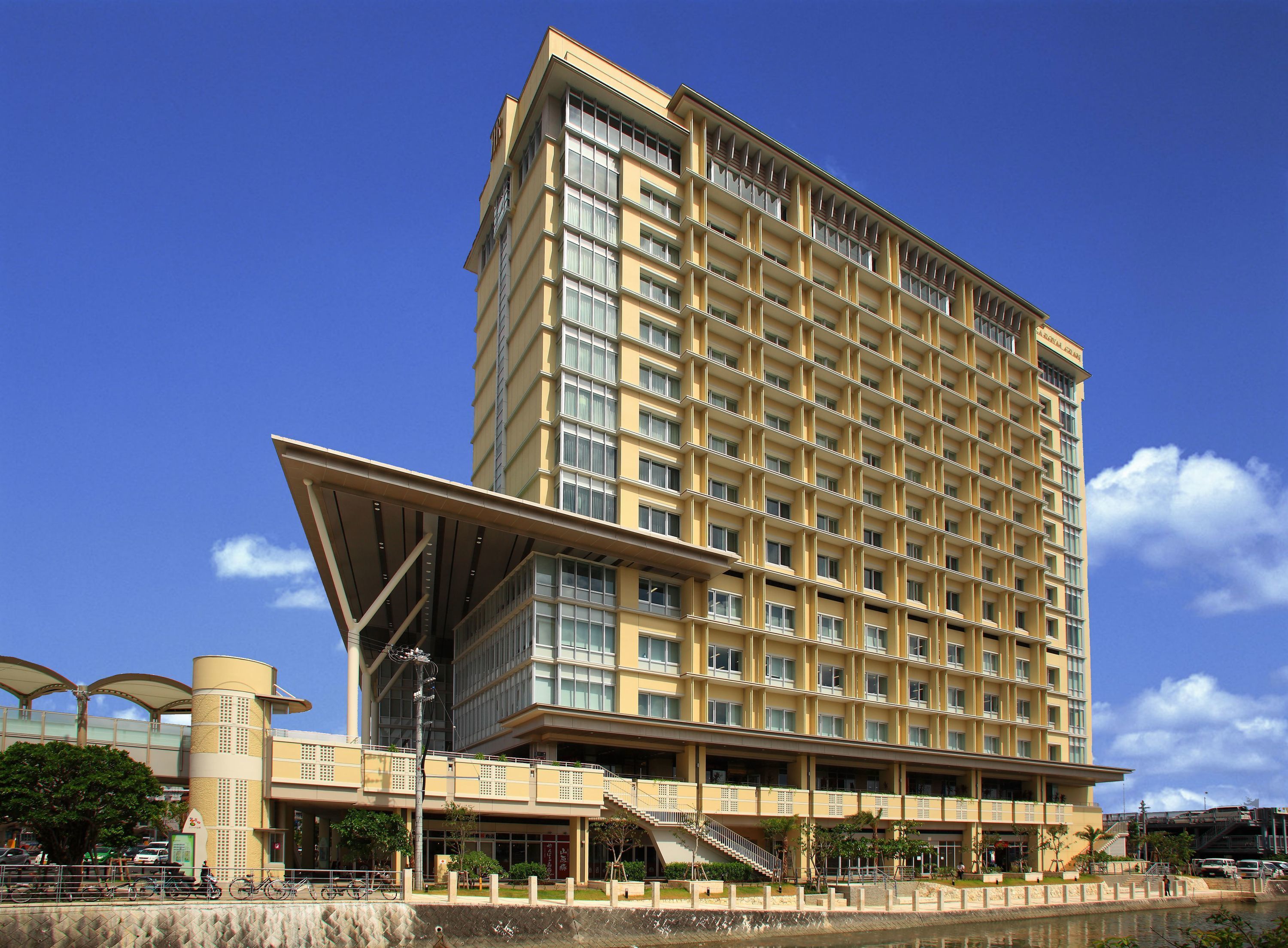 A multi-story hotel with a modern design, featuring a prominent overhanging structure at the ground level.
