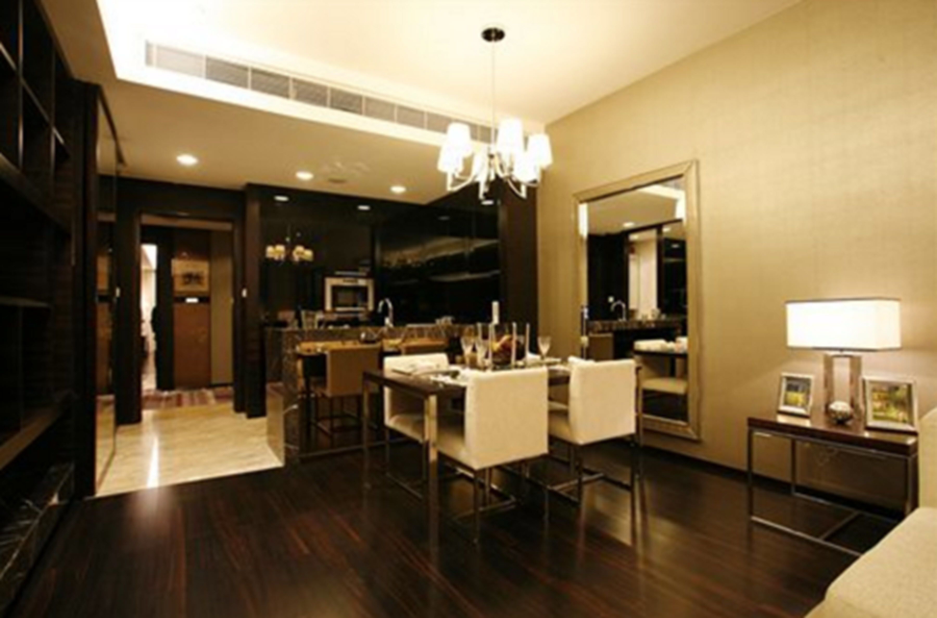 A modern hotel room with a dining area, a large mirror, and a chandelier.