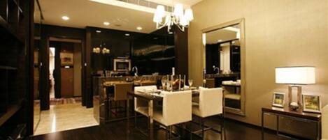 A modern hotel room with a dining area, a large mirror, and a chandelier.
